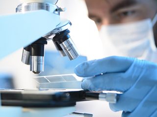 A scientist placing a slide under a microscope